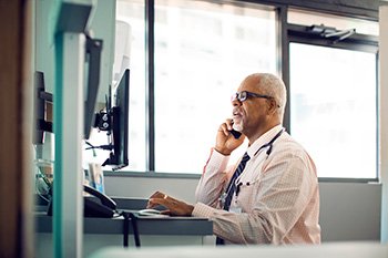 physician talking on phone looking at computer
